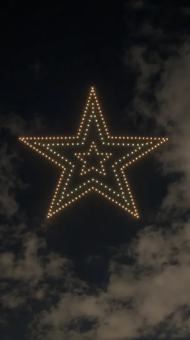 Hundreds of drones forming a glowing Christmas star in the night sky